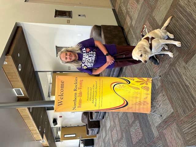 Cheryl standing in from of the Northern Rockies sign